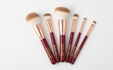 Set of makeup brushes with red handles and gold accents on a white background